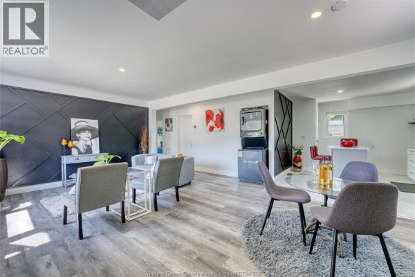 Living room with grey sectional sofa, decorative wall paneling, and artwork. - 3414 Dominion Avenue, Windsor