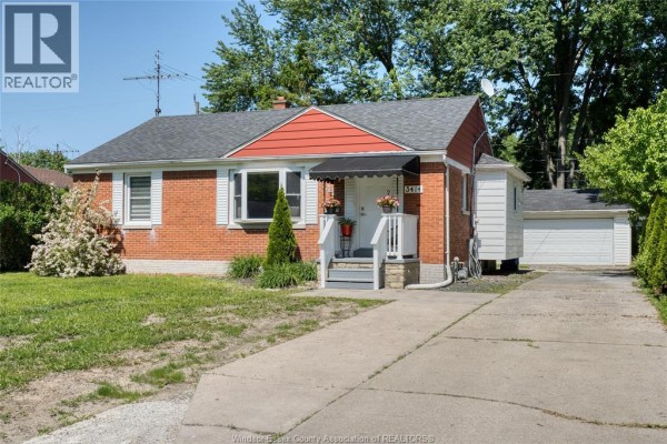 Living room with a bay window showing a tree-lined street view. - 3414 Dominion Avenue, Windsor