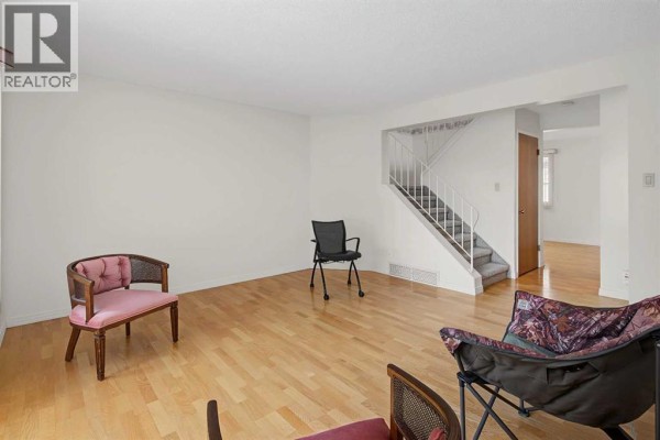 Living room with light wood floors, white walls, and a staircase. - 3414 Morley Trail Nw, Calgary
