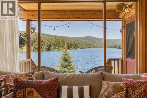 View from indoors of a lake and forest through a screened-in porch with furniture. - 3415-3421 Princeton Summerland Road, Princeton