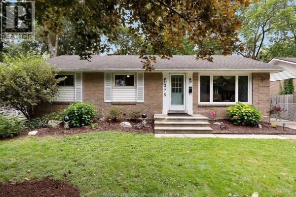 Close-up front view of the brick bungalow showing windows, landscaping, and entryway. - 3415 Randolph, Windsor