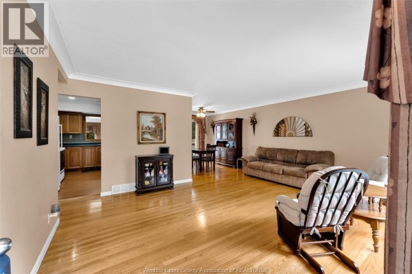 Living room with hardwood floors, beige walls, a sofa, armchair, and dining area beyond. - 3415 Randolph, Windsor