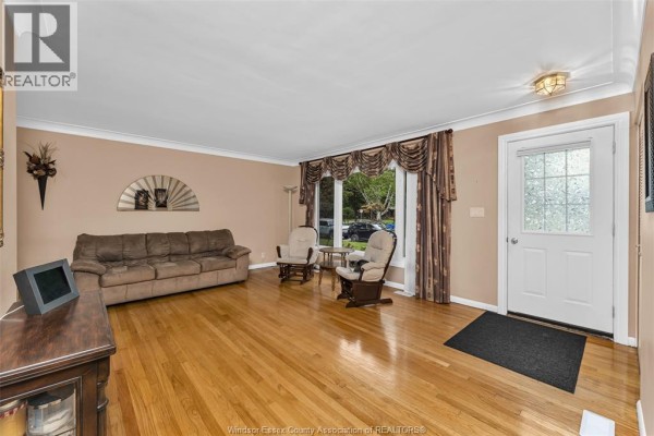 View of the living room showing a sofa, armchairs, hardwood floors, and front door. - 3415 Randolph, Windsor