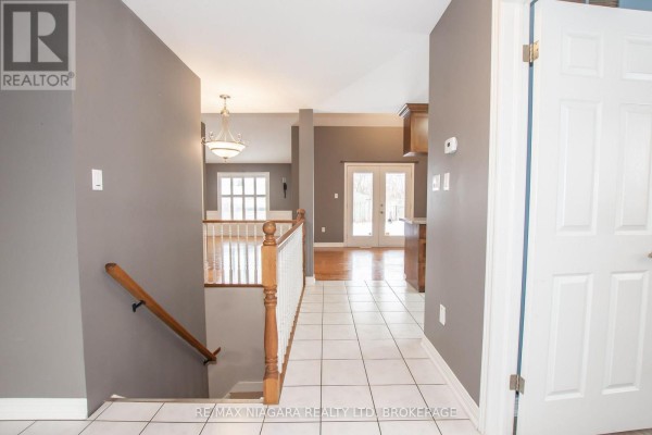 Interior hallway with beige tile floors, white baseboards, and grey walls. - 3417 Michelle Court, Niagara Falls