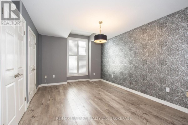 Interior view of a hallway with white tile floors and wooden railing for stairs. - 3417 Michelle Court, Niagara Falls