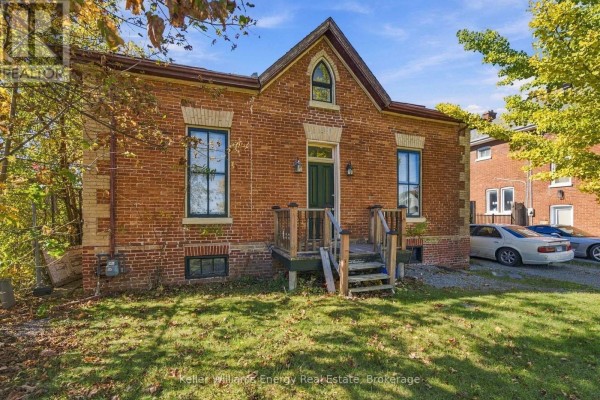 Street view of brick house with driveway and surrounding trees - 342 Mary Street N, Oshawa