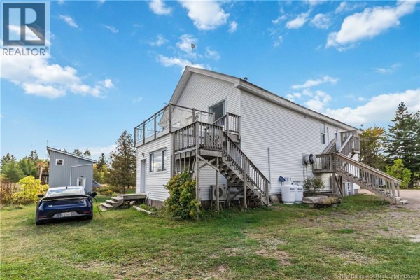 Exterior view of the back of the building with a deck and parking area, featuring a car and grassy space. - 342 Route 970, Baie Verte