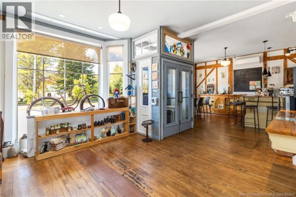 Interior view of the commercial space with wooden floors, large windows, and a display area with shelves. - 342 Route 970, Baie Verte