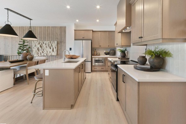 Open concept living, dining, and kitchen area with light wood floors and neutral decor. - 342 Stiles Wy, Leduc