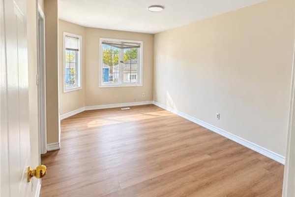 Empty room with bay windows, neutral walls, and light wood laminate flooring. - 343 Dalhousie Street, Brantford