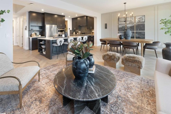 Open concept living and dining area with a dark wood kitchen island, dining table, and fireplace. - 344 Stiles Wy, Leduc