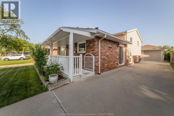 A closer look at the side of the house at 3444 Hemlock, Windsor, showing the brickwork, porch, and concrete driveway. - 3444 Hemlock, Windsor