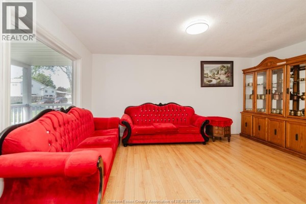 Living room of 3444 Hemlock, Windsor, featuring two red velvet sofas, a wooden cabinet, and light wood flooring. - 3444 Hemlock, Windsor
