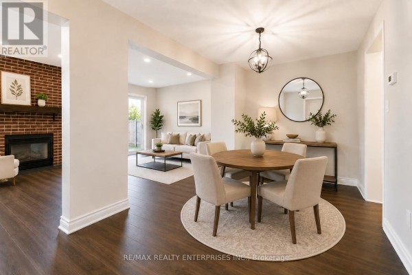 Dining area with a round wooden table, four upholstered chairs, and an adjoining living room. - 3446 Ash Row Crescent N, Mississauga
