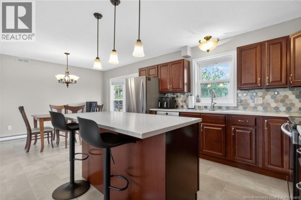 Kitchen with dark wood cabinets, quartz island with black stools, stainless steel appliances, and hex tile backsplash. - 3448 Route 126, Lutes Mountain