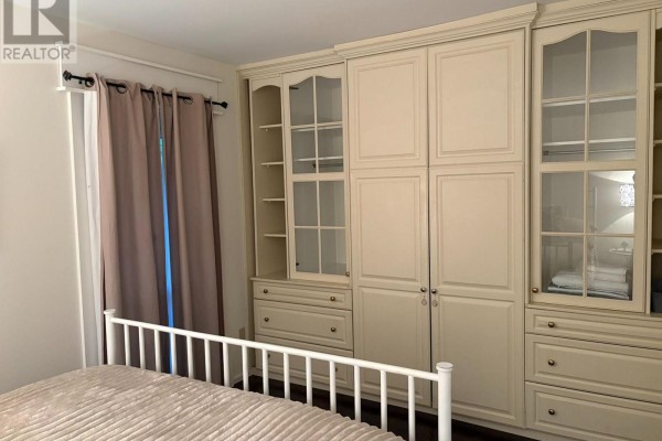 Bedroom with a large cream-colored built-in wardrobe and floor-to-ceiling curtains. - 345 - 11 Harbour Street W, Collingwood