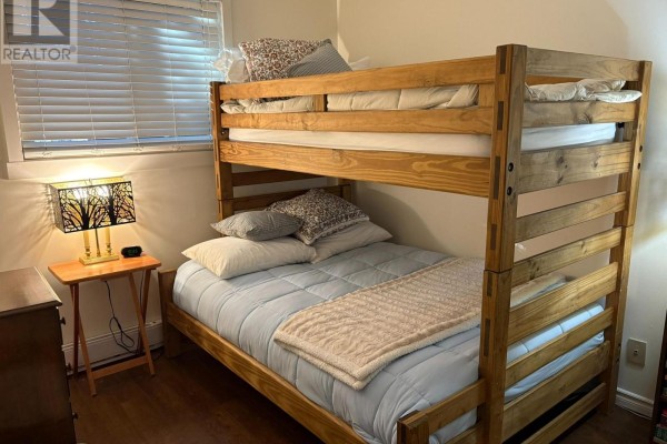 Bedroom with a wooden bunk bed, pillows, blankets, and a small nightstand. - 345 - 11 Harbour Street W, Collingwood