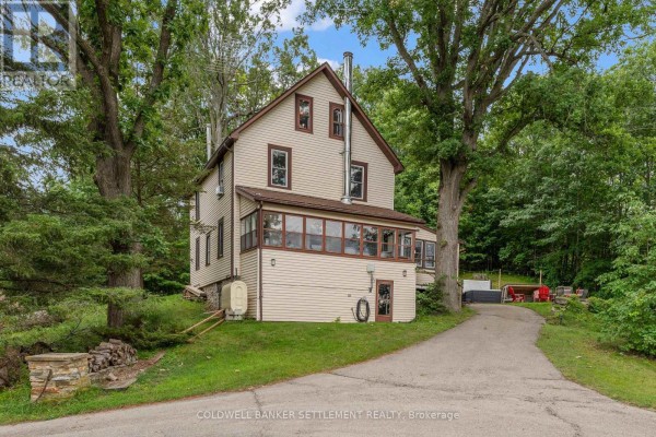 Rear exterior view of the house with a fire pit, hot tub, and outdoor seating area. - 345 Battams Road, Rideau Lakes