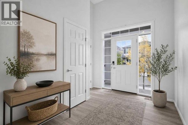 Bright entryway with double white doors, a console table, artwork, and potted plants. - 345 Yorkville Road Sw, Calgary