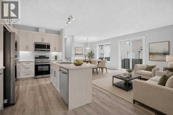 Open concept kitchen and living area with light wood cabinets, stainless steel appliances, and dining area. - 345 Yorkville Road Sw, Calgary