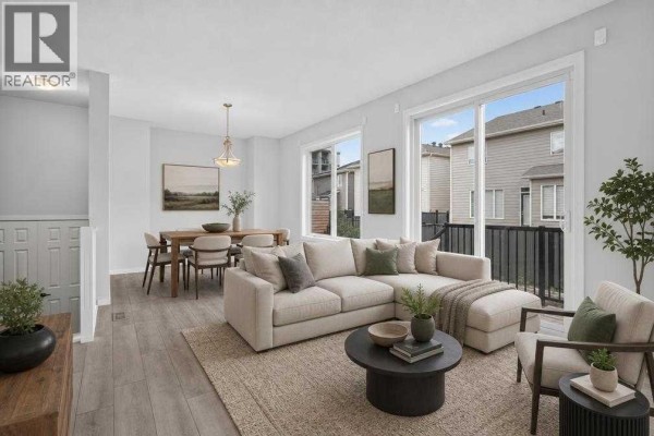 Living and dining area with a large sectional sofa, coffee table, and dining set near sliding glass doors. - 345 Yorkville Road Sw, Calgary
