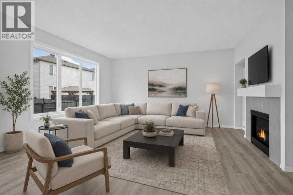 Spacious living room with a large sectional sofa, fireplace, and large windows overlooking the backyard. - 345 Yorkville Road Sw, Calgary