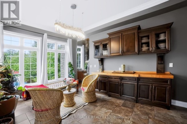 Kitchen with dark wood cabinets, butcher block counter, and wicker chairs - 345305 15th Side Road Amaranth