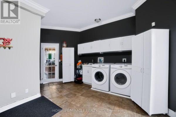 Laundry room with white cabinets, washer, dryer, sink, and tile floors - 345305 15th Side Road Amaranth