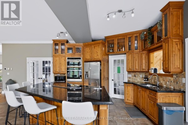 Kitchen with wood cabinets, island, and stainless steel appliances - 345305 15th Side Road Amaranth