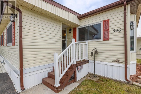 Close-up of the mobile home's entrance with white railings and dark wooden steps. - 346 - 3033 Townline Road, Fort Erie