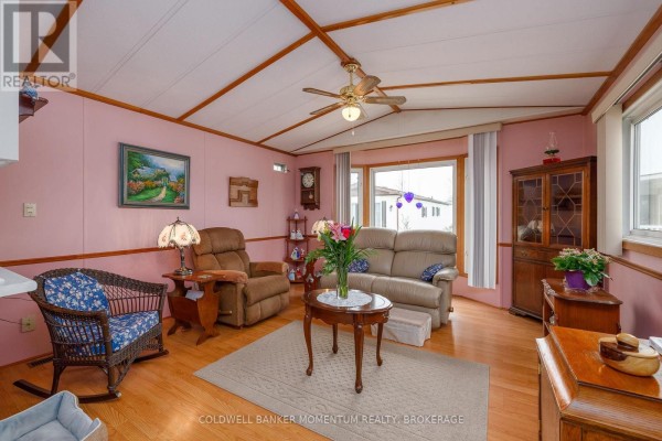Living room with pink walls, light wood floors, a sofa, recliner, and rocking chair. - 346 - 3033 Townline Road, Fort Erie