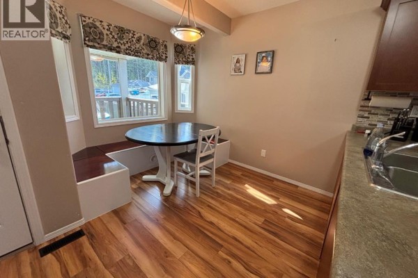 Dining area with a round table, bench seating, and a window overlooking the street. - 346 Boutin Avenue, Hinton
