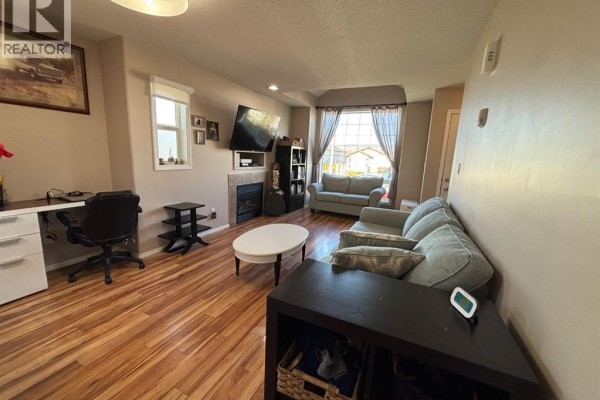 Spacious living room featuring a sofa, fireplace, television, desk area, and window views of the neighborhood. - 346 Boutin Avenue, Hinton