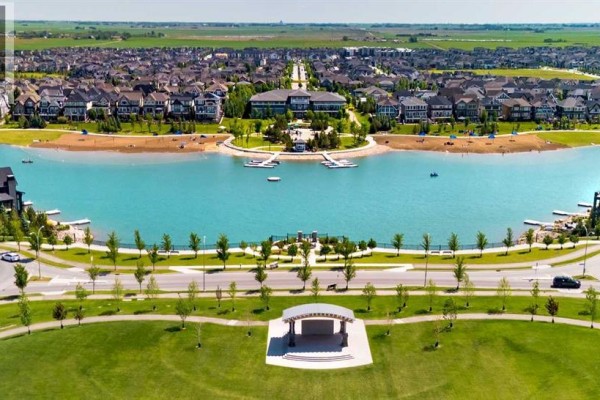 Aerial view of a lake community with houses, a beach, and a central park with amphitheater. - 346 Magnolia Way Se, Calgary