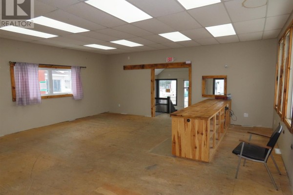Interior commercial space with a wooden counter, chairs, and an open doorway. - 346 North St, Sault Ste Marie