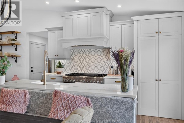 Modern kitchen with island, quartz counters, gas range, tile backsplash, and pantry - 346 Texas Road Amherstburg