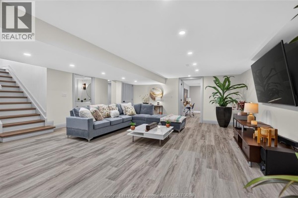 Blue sectional sofa, modern flooring, and mounted TV in living room - 346 Texas Road Amherstburg