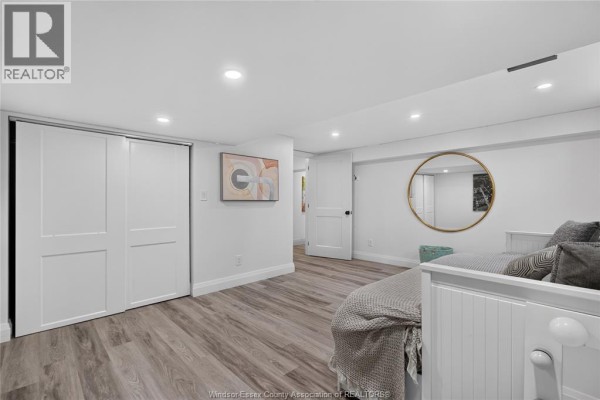 Bedroom with sliding closet doors, laminate floors, and a round gold mirror - 346 Texas Road Amherstburg