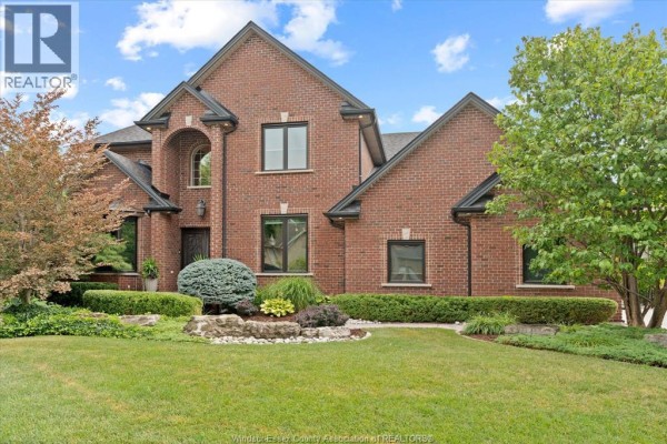 Red brick two-story house with manicured lawn and landscaping, arched entryway with glass door. - 3460 Huntington Avenue, Windsor