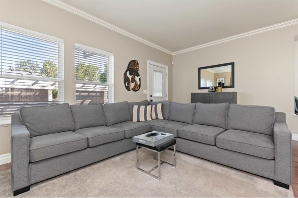 A bedroom with a white duvet, a dresser, a television, and two white bi-fold closets. - 34609 7 Avenue, Abbotsford