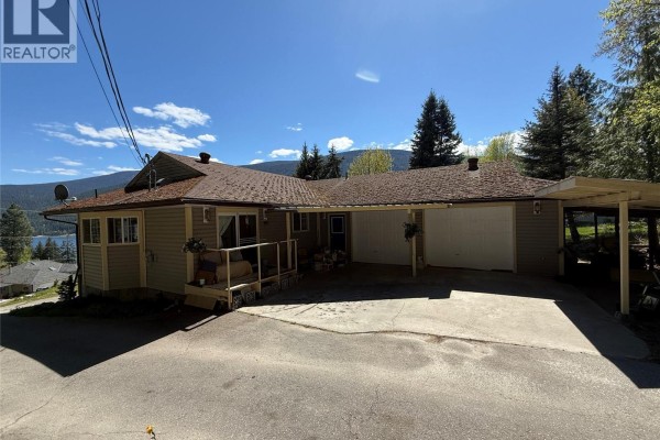 Single-story house with beige siding, a covered carport, and garage doors. - 3461 Bodard Road, Nelson