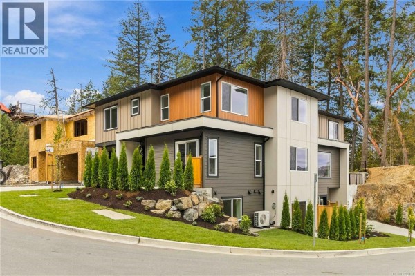 Side view of a modern duplex with multi-tone siding, landscaping, and a sloped driveway. - 3462 Merlot Terr, Langford