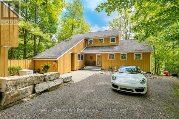 Interior stone accent wall with a black wood stove, firewood, and wooden cabinets. - 347 Prinyers Cove Crescent, Prince Edward County