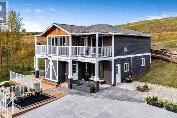 Dark gray house with white trim, white railings, and wooden decks. - 3472c Township Road 290 A, Rural Mountain View County