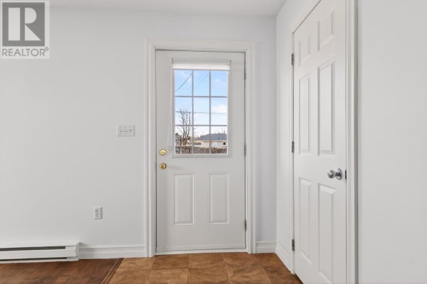 Corner of a room with dark wood floors, shiplap accent wall, air conditioner, and a window. - 348 Jennifer Street, Summerside