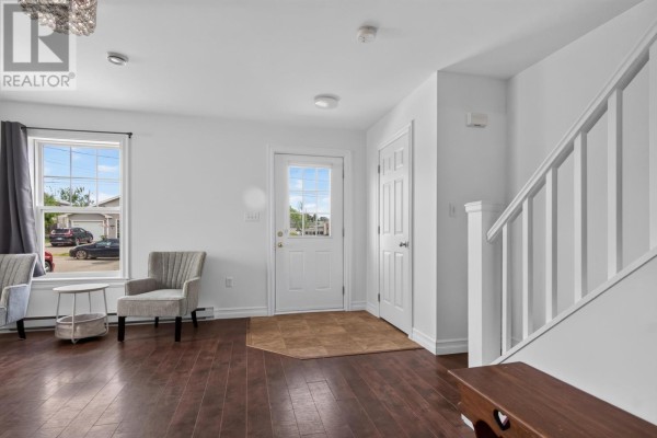 Interior of a room with dark wood floors, two windows, a door, and a decorative light fixture. - 348 Jennifer Street, Summerside