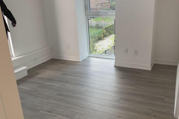 Empty room with light grey wood-look flooring and a large window overlooking greenery. - 349 - 500 Wilson Avenue, Toronto
