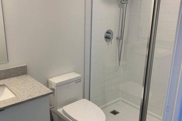 Bathroom with a white toilet, granite-top vanity, and a glass-enclosed shower stall. - 349 - 500 Wilson Avenue, Toronto