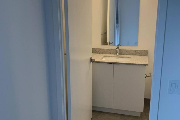 View of a bathroom vanity with a granite countertop, white sink, and mirror. - 349 - 500 Wilson Avenue, Toronto