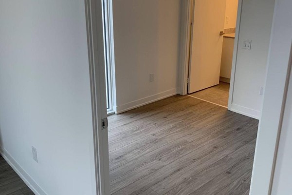 Hallway view of a room with light grey wood-look flooring and white walls. - 349 - 500 Wilson Avenue, Toronto